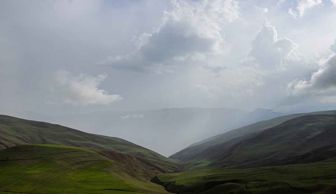 a grassy valley with clouds above