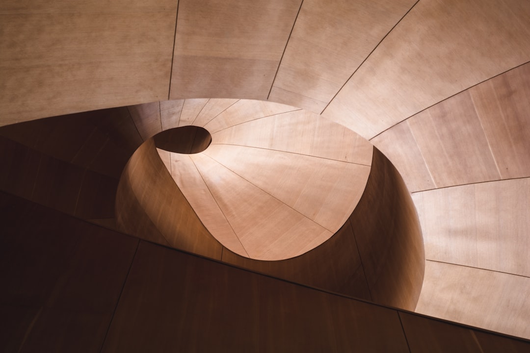 A curved wooden staircase spiraling into a dark central void