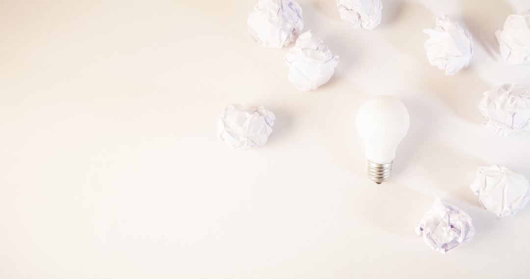 Light bulb surrounded by crumpled paper balls